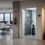 Estintore a CO2 in un ufficio moderno vicino a un quadro elettrico, con open space e archivio sullo sfondo